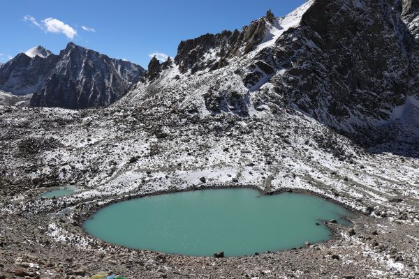 Turquoise glacial lake surrounded by snow-covered peaks near Mount Kailash