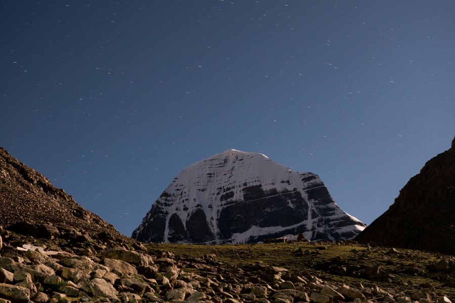 Snow-capped Mount Kailash under clear blue skies with rocky foreground in Tibet